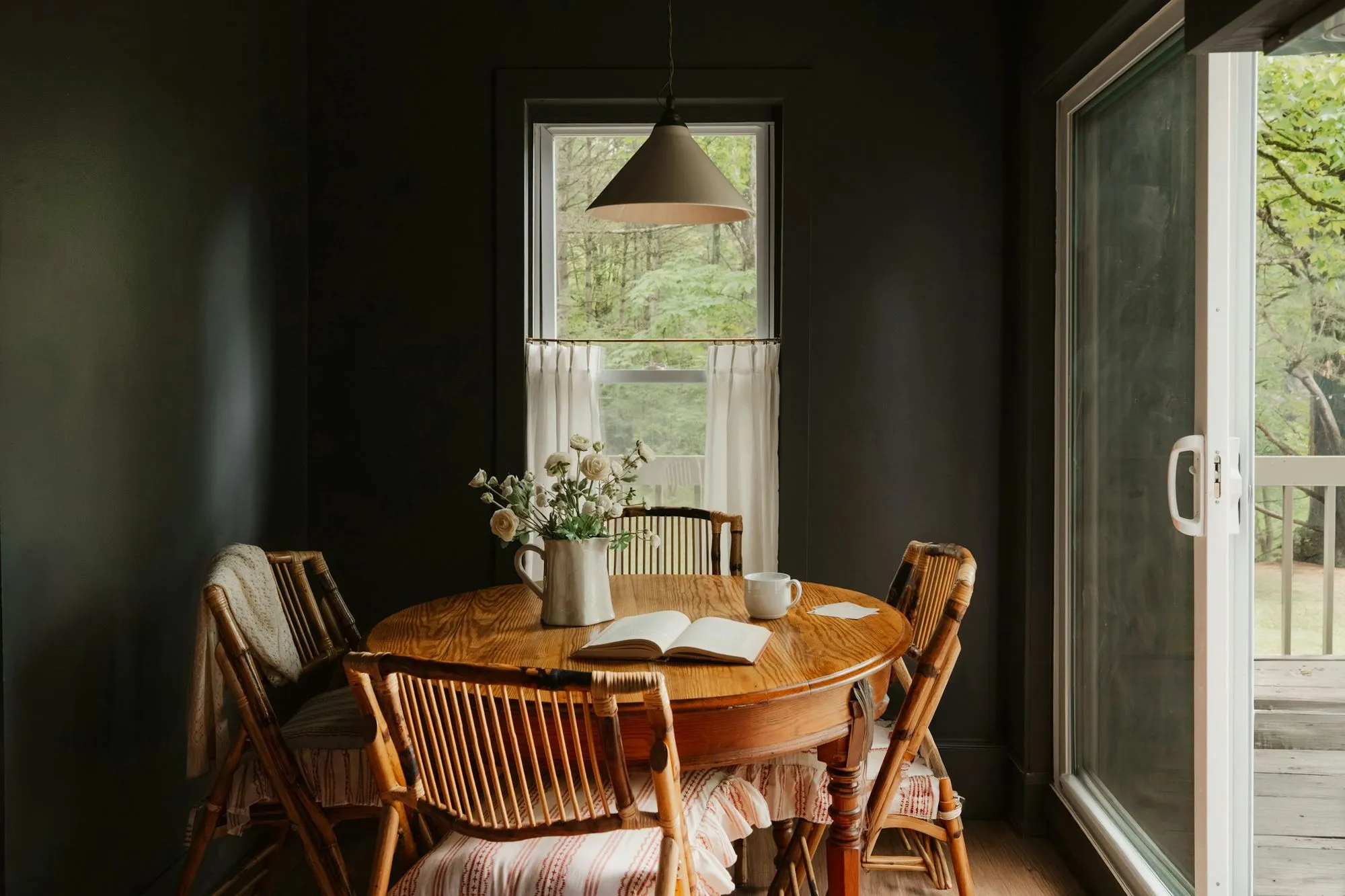 Round oak table with bamboo chairs under a pendant light by a sliding glass door