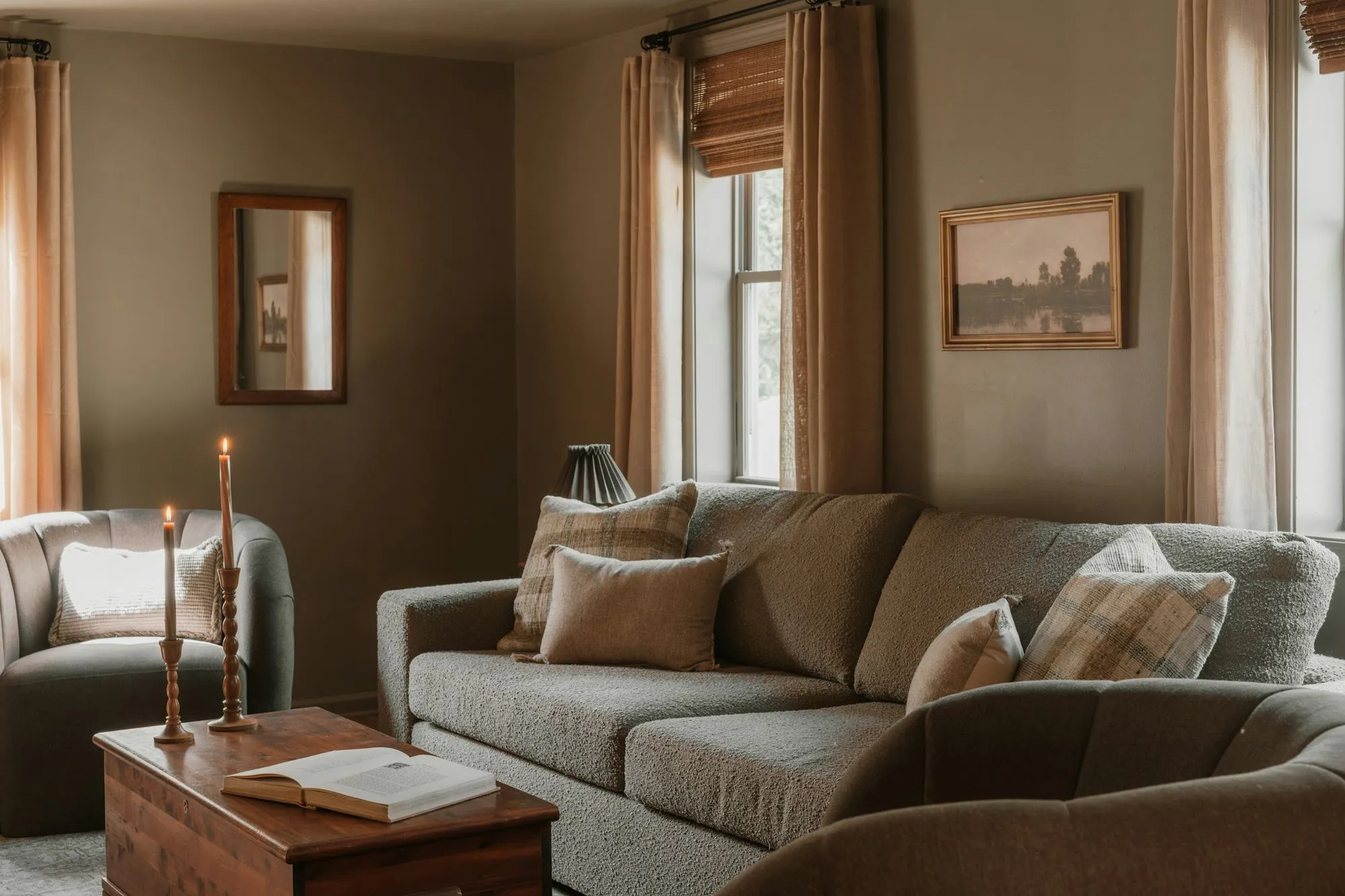 Sitting room with a grey sofa, a wood trunk and linen curtains in afternoon light